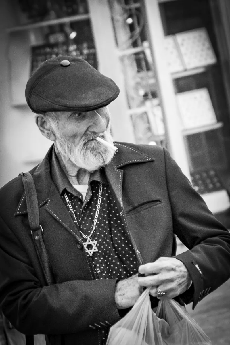Bearded man in a cap with a cigarette and hanging necklaces